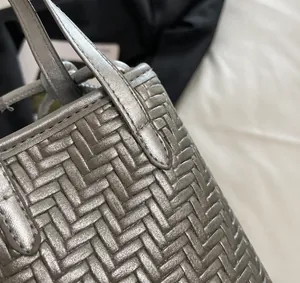 Détail de la texture en cuir tressé argenté et coutures renforcées sur le mini sac