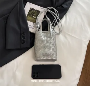 Mini sac tissé argenté avec téléphone portable pour référence de taille sur fond mode