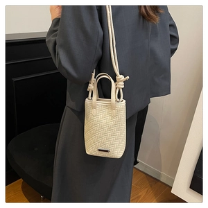 Gros plan du mini sac seau crème avec texture tissée, bandoulière nouée et détails