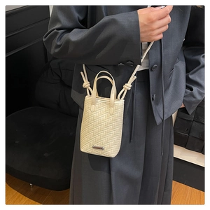 Détail du mini sac bandoulière tissé crème avec plaque en métal et double bandoulière