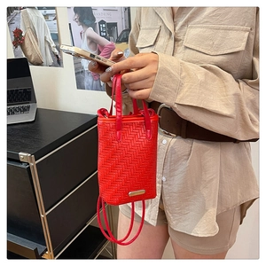 Détail du sac bandoulière rouge tissé avec motif à chevrons et plaque en métal