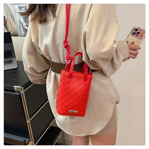 Détail du sac bandoulière tressé rouge avec boucle et texture cuir élégante