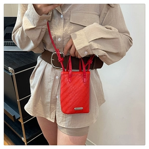Détail du mini sac à bandoulière tressé rouge avec logo argenté et texture PU