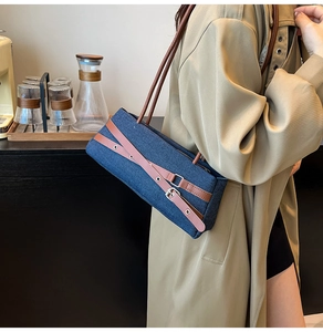 Close-up of blue denim baguette bag with brown leather strap in a cafe setting