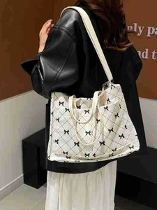 Minimalist white tote bag with black bow pattern shown in a lifestyle model back view
