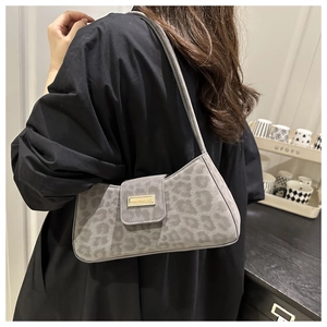 Détail du sac à main léopard gris en daim avec boucle dorée porté à l'épaule