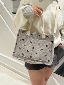 Minimalist light gray corduroy tote bag with black bow pattern and wide shoulder strap