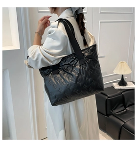 Detailed view of black quilted tote bag with bow texture and wide canvas shoulder strap