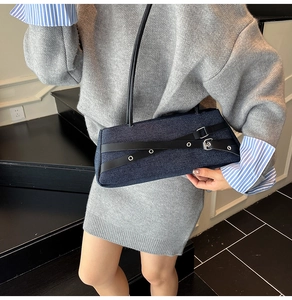 Detail of denim shoulder bag featuring black leather straps and silver metal buckles