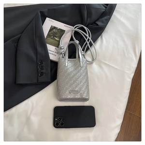 Mini sac cabas tressé argenté posé à côté d'un smartphone pour illustrer sa taille