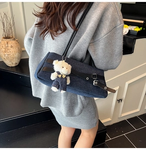 Détail du sac sous l'aisselle en denim bleu foncé avec un adorable pendentif en peluche