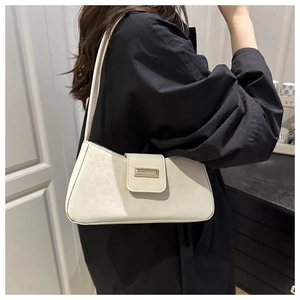 Détail du sac à bandoulière crème avec boucle métallique et cuir texturé sur un modèle