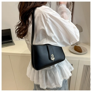 Détail du sac à bandoulière en cuir noir mat avec boucle dorée en forme de gourde