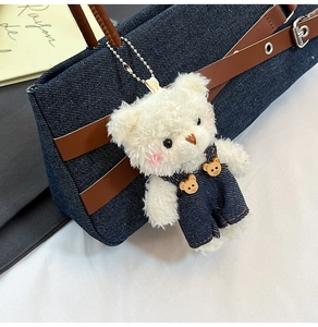 Gros plan du pendentif ours en peluche blanc avec salopette en jean et boutons en bois