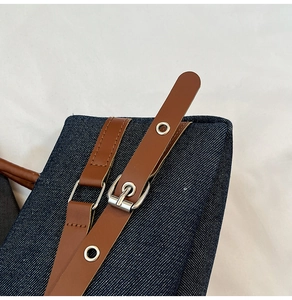Détail du sac en denim bleu avec bandoulière en cuir marron et boucle en métal argenté