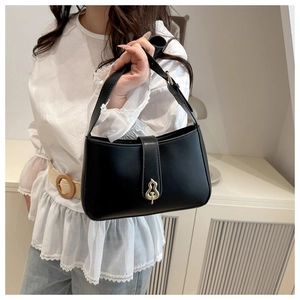 Detail of elegant black faux leather bag featuring a golden gourd-shaped metal clasp buckle