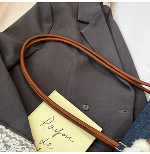 Détail du sac à main en denim avec bandoulière en cuir marron et breloque pompon blanc