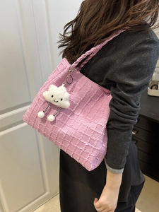 Pink embossed grid shoulder bag with plush cloud charm shown on a female model