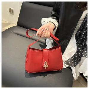 Close-up of red leather handbag featuring a decorative gold gourd shaped metal buckle lock
