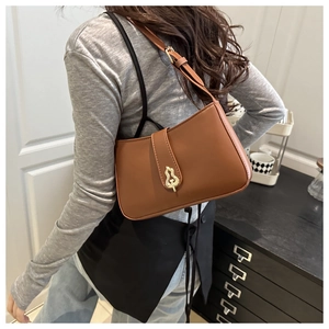 Détail d'un sac à main en cuir marron vintage avec boucle dorée décorative sur le rabat