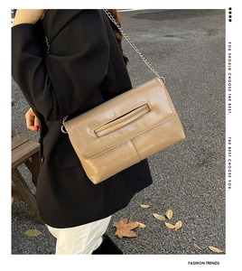 Detail of khaki leather envelope crossbody bag with silver chain strap in street style