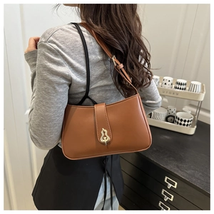 Détail du sac à bandoulière en cuir marron avec une boucle dorée unique en forme de gourde