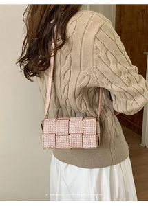 Detail of a beige woven crossbody bag with vintage monogram patterns and premium texture