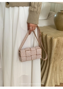 Detail of woven plaid crossbody bag with long strap shown in a cozy interior setting