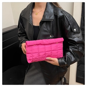 Detail of hot pink quilted puffer clutch bag with gold button and square texture