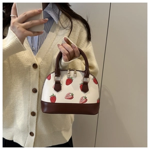Detail of strawberry print dome bag with brown PU leather trim and gold hardware accents