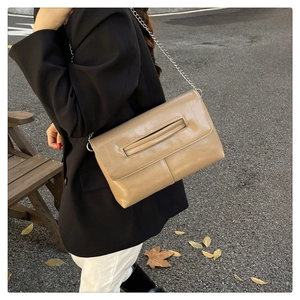 Outdoor shot of light brown chain crossbody bag featuring smooth PU leather and flap design