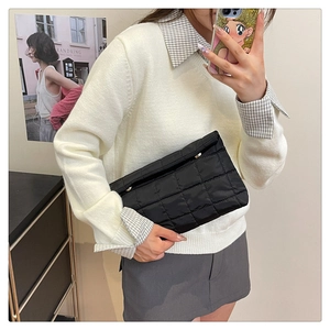 Detail van zwarte gewatteerde puffer envelop clutch met chique ruitjespatroon textuur