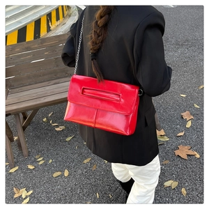 Macro detail of glossy red leather shoulder bag with silver chain strap and flap design