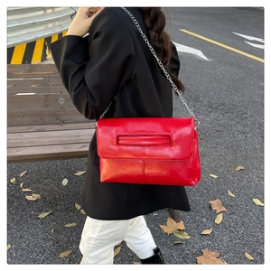 Street style view of a red glossy leather envelope clutch with silver chain strap