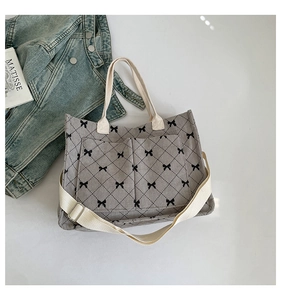 Detail of gray corduroy tote bag with black diamond quilt patterns and bow tie details