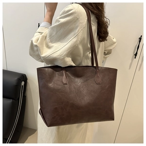 Dettaglio della borsa tote grande marrone scuro in ecopelle vintage sulla spalla