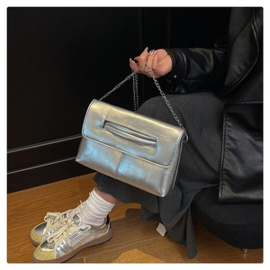 Detail of silver metallic envelope clutch with chain strap and reflective mirror finish