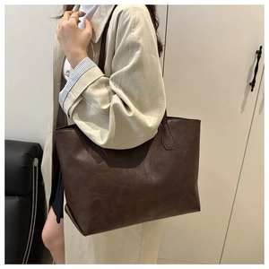 Dettaglio della borsa tote vintage marrone scuro in pelle opaca indossata dalla modella