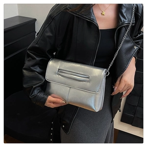 Detail of silver metallic chain bag with sleek envelope design and integrated hand handle