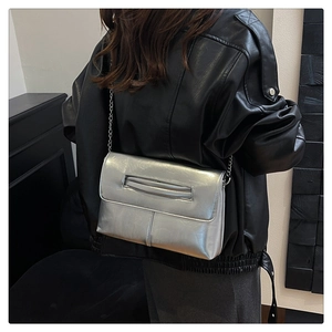 Silver metallic chain bag shown against a black leather jacket for style detail