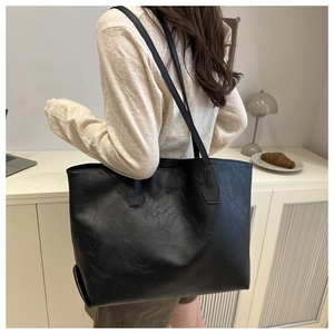 Dettaglio della borsa tote nera con trama in pelle crackle vintage e manico robusto
