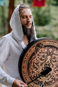 Detail of handmade Shamanic drum featuring a bear totem pattern in a forest setting