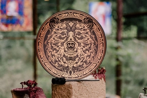 Detail of shamanic drum featuring a bear totem pattern and drumstick on a stone surface