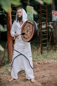 Detail view of ethnic shaman drum with bear totem print and matching folk style apparel