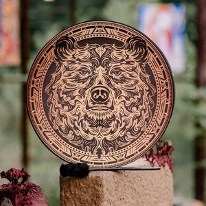 Handmade shamanic drum with brown bear design and mallet on a natural stone base