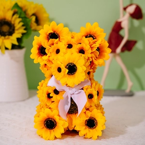 Close-up of a handmade sunflower bear with yellow artificial flowers and white ribbon bow
