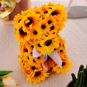 Close-up of bear figurine crafted with sunflower petals and white ribbed ribbon bow