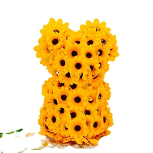 Cute bear gnome figurine covered in yellow sunflowers on a woven mat for home decor