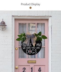Detail of a black round welcome sign with dog theme hanging on a pink wooden door