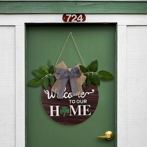 Detail of wooden welcome home sign with clover design and burlap bow on a green door